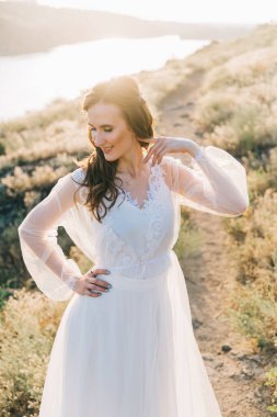 Şatafatlı beyaz gelinlikli gelin gün batımında doğada