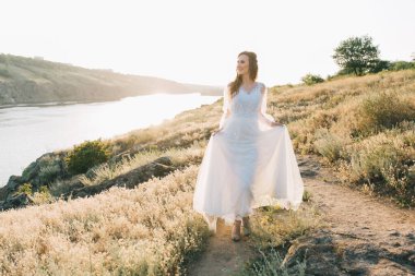 Şatafatlı beyaz gelinlikli gelin gün batımında doğada