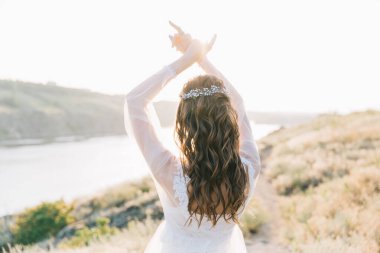 Şatafatlı beyaz gelinlikli gelin gün batımında doğada