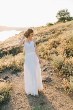 Şatafatlı beyaz gelinlikli gelin gün batımında doğada