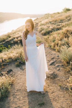 Şatafatlı beyaz gelinlikli gelin gün batımında doğada