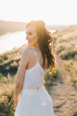 Şatafatlı beyaz gelinlikli gelin gün batımında doğada