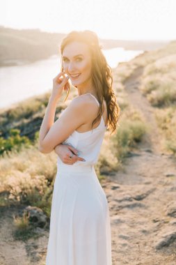 Şatafatlı beyaz gelinlikli gelin gün batımında doğada