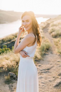 Şatafatlı beyaz gelinlikli gelin gün batımında doğada