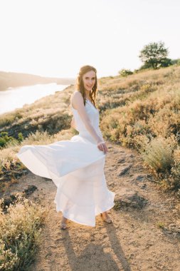 Şatafatlı beyaz gelinlikli gelin gün batımında doğada