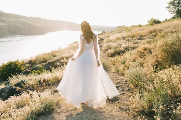 Şatafatlı beyaz gelinlikli gelin gün batımında doğada