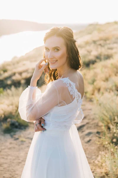 日落时穿着华丽的白色婚纱的新娘 — 图库照片