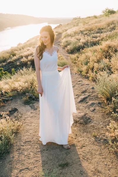 日落时穿着华丽的白色婚纱的新娘 — 图库照片