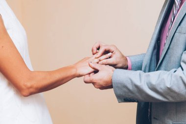 Bir çift gelin ve damadın elleri alyans değiş tokuşu yapıyor.