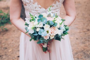 Düğün buketi gelinin elinde ve koltukta, düğün detayları ve ayakkabılar.