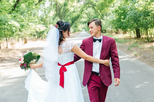 Ženich Burgundském Obleku Nevěsta Bílých Šatech Červenou Stuhou Vínovou Kyticí — Stock fotografie