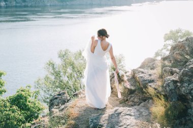 Şatafatlı beyaz gelinlikli gelin gün batımında doğada