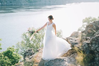 Şatafatlı beyaz gelinlikli gelin gün batımında doğada