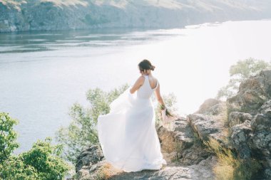 Şatafatlı beyaz gelinlikli gelin gün batımında doğada