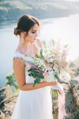 Şatafatlı beyaz gelinlikli gelin gün batımında doğada