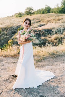Şatafatlı beyaz gelinlikli gelin gün batımında doğada