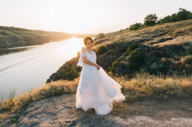 Şatafatlı beyaz gelinlikli gelin gün batımında doğada