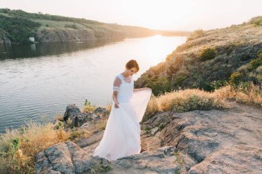 Şatafatlı beyaz gelinlikli gelin gün batımında doğada