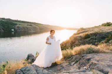 Şatafatlı beyaz gelinlikli gelin gün batımında doğada