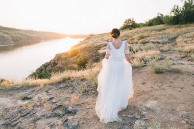 Şatafatlı beyaz gelinlikli gelin gün batımında doğada