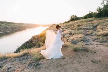 Şatafatlı beyaz gelinlikli gelin gün batımında doğada