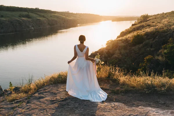 日没時に自然の中で豪華な白いウェディングドレスで花嫁 — ストック写真