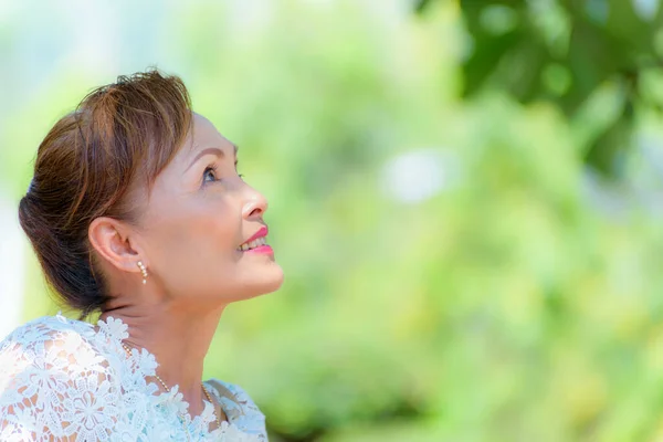 一位身穿泰式服装的健康的亚洲中年女性的脸 站在户外的画像老太太 在公园里开心地微笑着 在绿树成荫的自然背景上复制空间 — 图库照片
