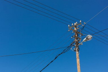 Telefon lamba direğine mavi gökyüzü karşı elektrik telleri ile