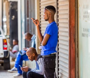 Johannesburg, Güney Afrika, 24 Ocak 2017, Afrikalı erkekler bir tarafında cep telefonlarını kullanarak yürümek