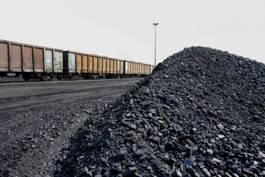Liman kıyı için taşıma için bir trende koymak için bekleyen bir demiryolu yan hatta yanındaki işlenmiş kömür yığınları