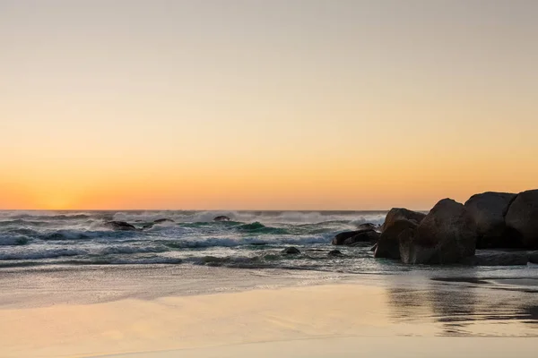 Ακατέργαστων κύματα στο ηλιοβασίλεμα σε μια αμμώδη παραλία με τις αντανακλάσεις του w — Φωτογραφία Αρχείου