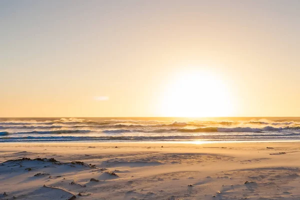 Ondas ásperas ao pôr do sol em uma praia de areia com reflexões sobre o w — Fotografia de Stock