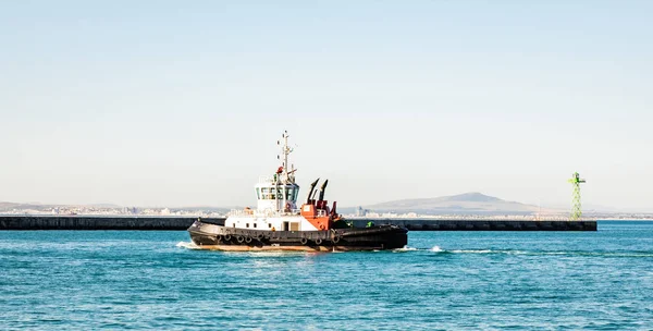 Pequeño remolcador que sale de la seguridad del puerto en el puerto comercial — Foto de Stock