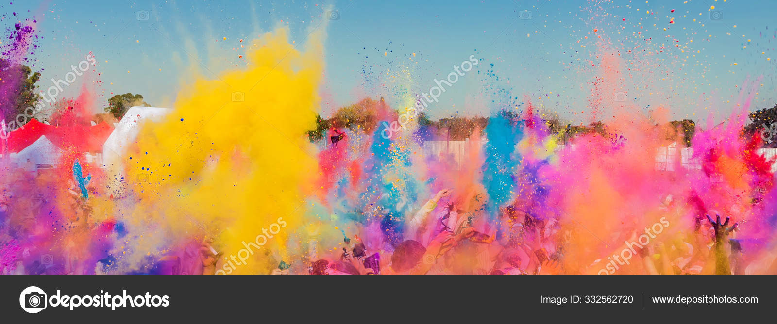 Crowd throwing bright colored powder paint in the air at Holi Fe