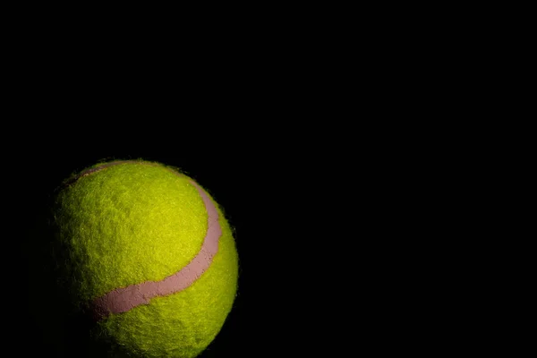 黒を背景に劇的な影を持つ明るい黄色のテニスボール — ストック写真