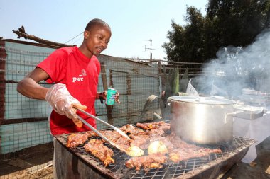 Soweto, Güney Afrika - 10 Eylül 2011: Afrikalı adam Soweto kentinin arka sokağında barbekü ızgarasında çalışıyor