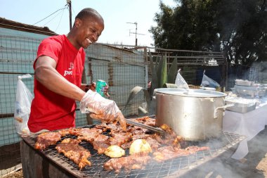 Soweto, Güney Afrika - 10 Eylül 2011: Afrikalı adam Soweto kentinin arka sokağında barbekü ızgarasında çalışıyor