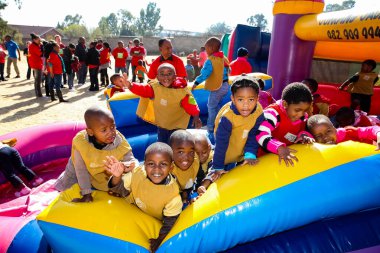 Soweto, Güney Afrika - 18 Temmuz 2012: Genç Afrikalı anaokulu çocukları parktaki atlama kalesinde eğleniyorlar 