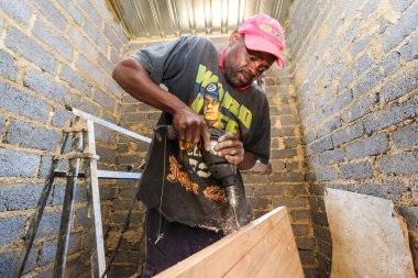 Soweto, Güney Afrika - 05 Eylül 2009: Afrikalı marangoz yerel bir kasabada küçük, ekonomik bir ev inşa etmek için bir Toplum Yardım Programı üzerinde çalışıyor