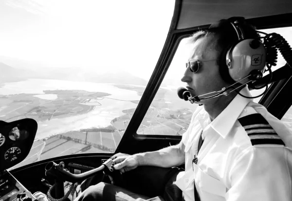 stock image Hermanus, South Africa - July 20, 2009: Caucasian male helicopter pilot flying a R44 type chopper over rural area