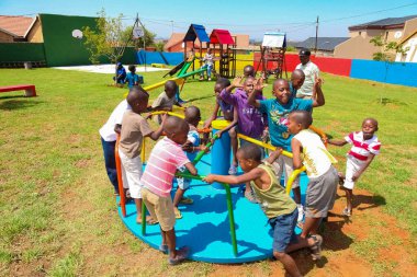 Soweto, Güney Afrika - 11 Aralık 2010: Atlıkarınca oynayan Afrikalı çocuklar ve yerel halk parkındaki diğer park ekipmanları