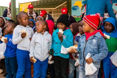 Soweto, Güney Afrika - 18 Temmuz 2016: Genç Afrikalı anaokulu çocukları bir anaokulunun bahçesinde sandviç yiyorlar 