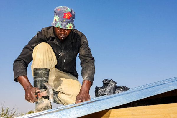 Совето, ЮАР - 05 сентября 2009 года: Программа по работе с населением, помогающая установить металлические крыши на небольшом доступном доме в местном игрушечном корабле.
