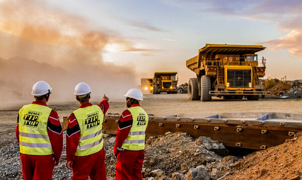 Rustenburg, South Africa, October 15, 2012, Large Dump Trucks transporting Platinum palladium ore for processing with mining safety inspectors in the foreground