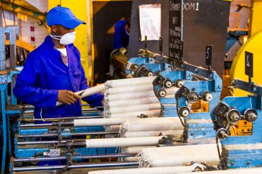 Johannesburg, Güney Afrika - 16 Ekim 2012: Copwinder Weft montaj hattı tezgahında çalışan Afrikalı fabrika işçisi