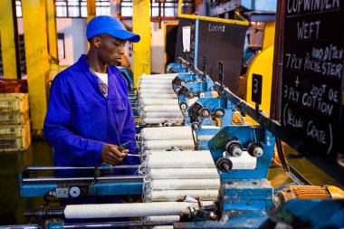 Johannesburg, Güney Afrika - 16 Ekim 2012: Copwinder Weft montaj hattı tezgahında çalışan Afrikalı fabrika işçisi