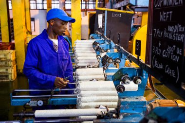 Johannesburg, Güney Afrika - 16 Ekim 2012: Copwinder Weft montaj hattı tezgahında çalışan Afrikalı fabrika işçisi