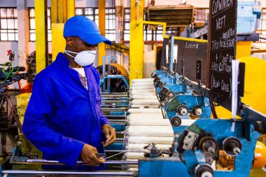 Johannesburg, Güney Afrika - 16 Ekim 2012: Copwinder Weft montaj hattı tezgahında çalışan Afrikalı fabrika işçisi