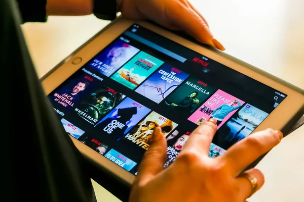 Johannesburg, Güney Afrika - 19 Ekim 2017: Netflix yayıncılık uygulamasını kullanan kadın el bilgisayarını tutuyor