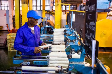 Johannesburg, Güney Afrika - 16 Ekim 2012: Copwinder Weft montaj hattı tezgahında çalışan Afrikalı fabrika işçisi
